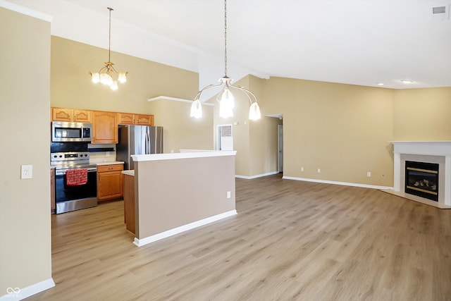 kitchen with pendant lighting, a fireplace, light hardwood / wood-style floors, and stainless steel appliances