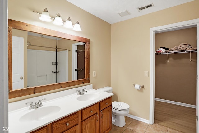 bathroom with a shower, tile patterned flooring, vanity, and toilet