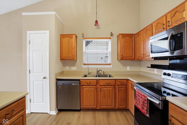 kitchen with sink, hanging light fixtures, vaulted ceiling, light hardwood / wood-style flooring, and appliances with stainless steel finishes