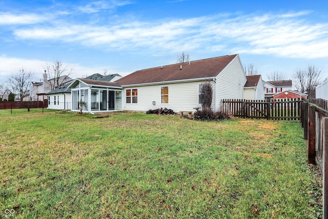 rear view of property featuring a sunroom and a yard