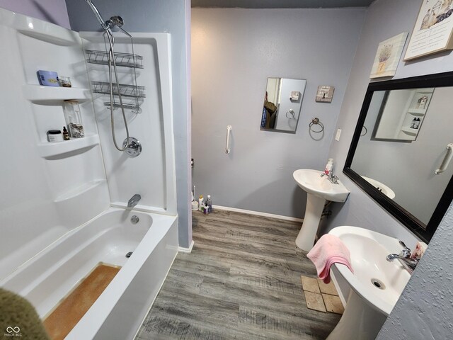 bathroom with hardwood / wood-style flooring, shower / bath combination, and sink