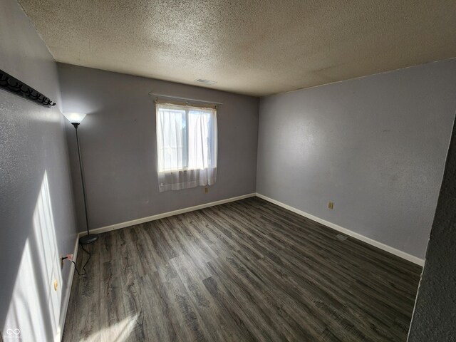 spare room featuring a textured ceiling and dark hardwood / wood-style floors