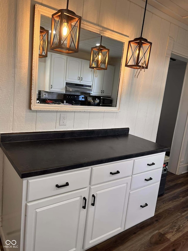 kitchen with wood walls, dark wood-type flooring, white cabinets, and hanging light fixtures