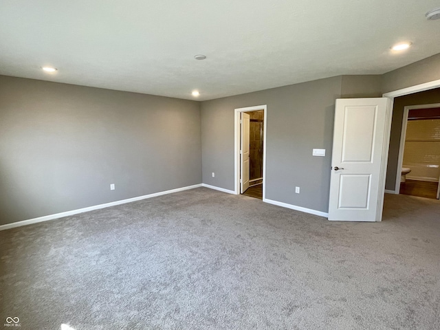 unfurnished bedroom featuring ensuite bath and dark carpet