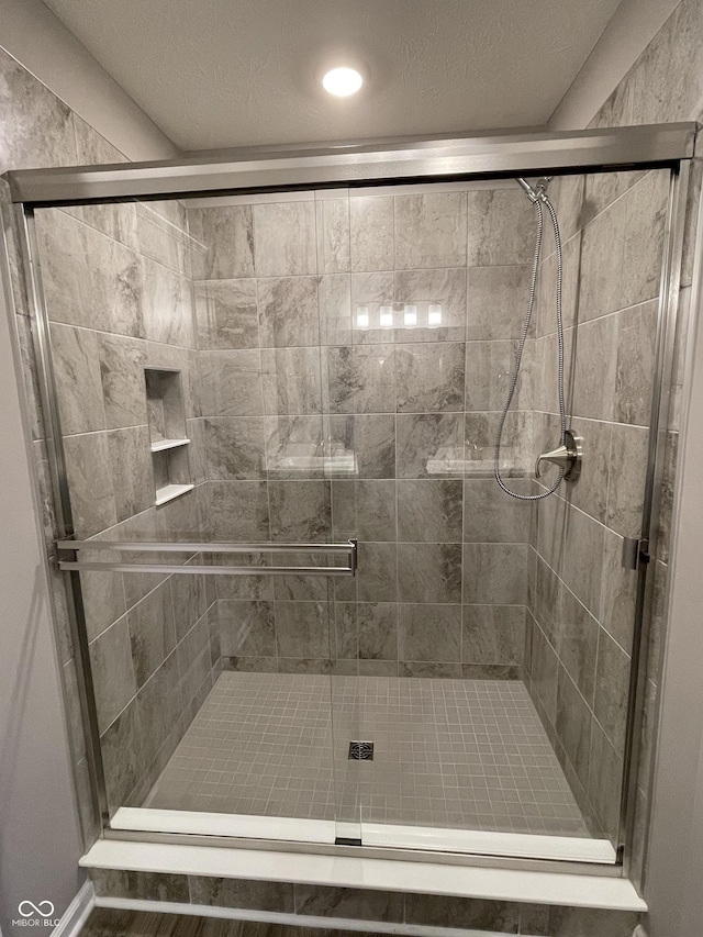 bathroom featuring a shower with shower door and a textured ceiling