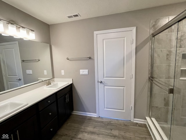 bathroom with vanity, a textured ceiling, hardwood / wood-style flooring, and a shower with door