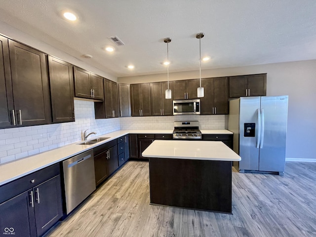 kitchen featuring light wood-type flooring, dark brown cabinetry, stainless steel appliances, pendant lighting, and a center island