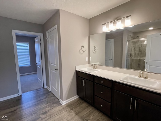 bathroom with hardwood / wood-style floors, vanity, a shower with door, and a textured ceiling