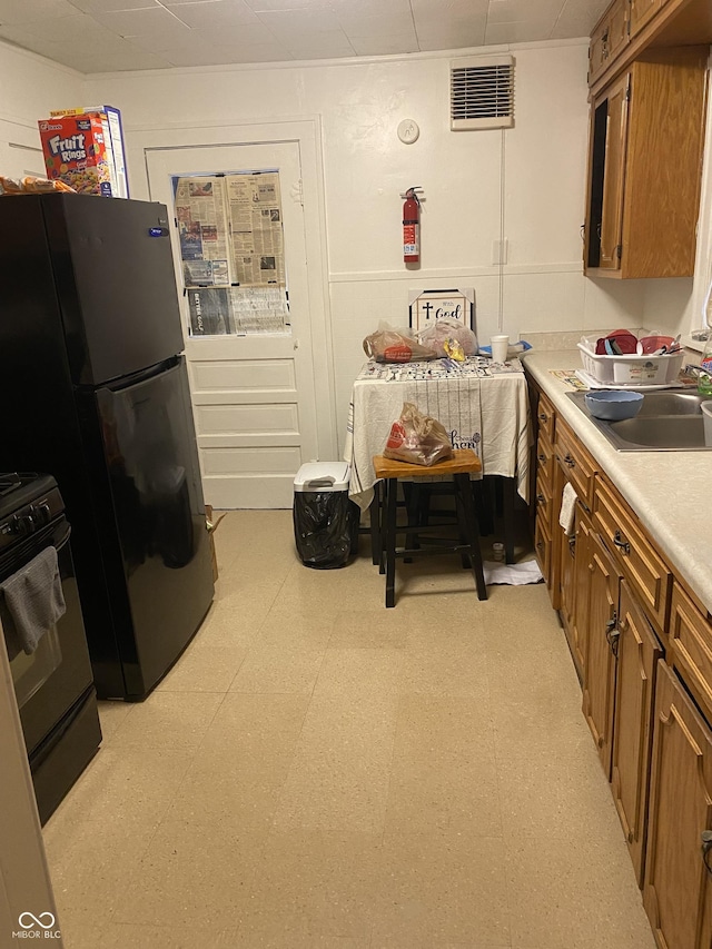 kitchen featuring stainless steel refrigerator, black / electric stove, and sink