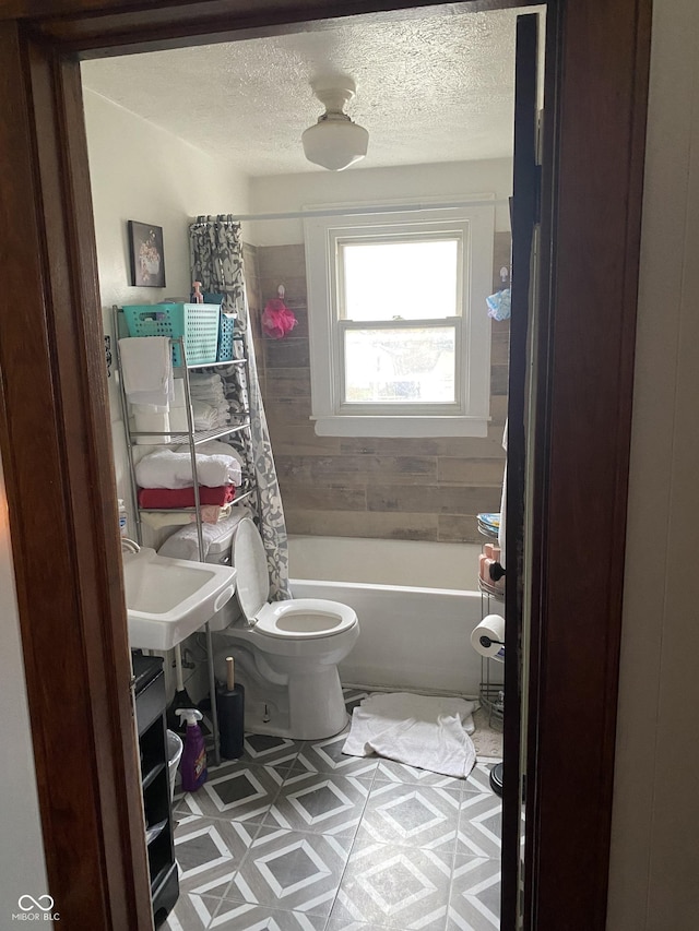 bathroom featuring shower / bath combo with shower curtain, a textured ceiling, and toilet