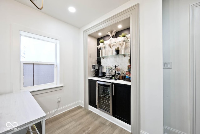 bar with light hardwood / wood-style flooring and beverage cooler