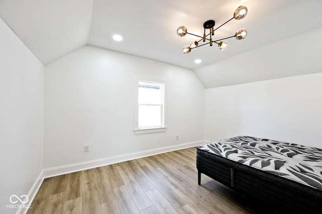 bedroom with light hardwood / wood-style floors, lofted ceiling, and an inviting chandelier