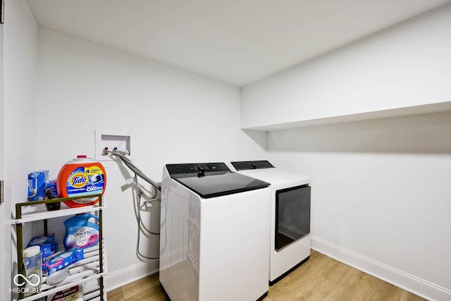 laundry room featuring independent washer and dryer and light hardwood / wood-style floors