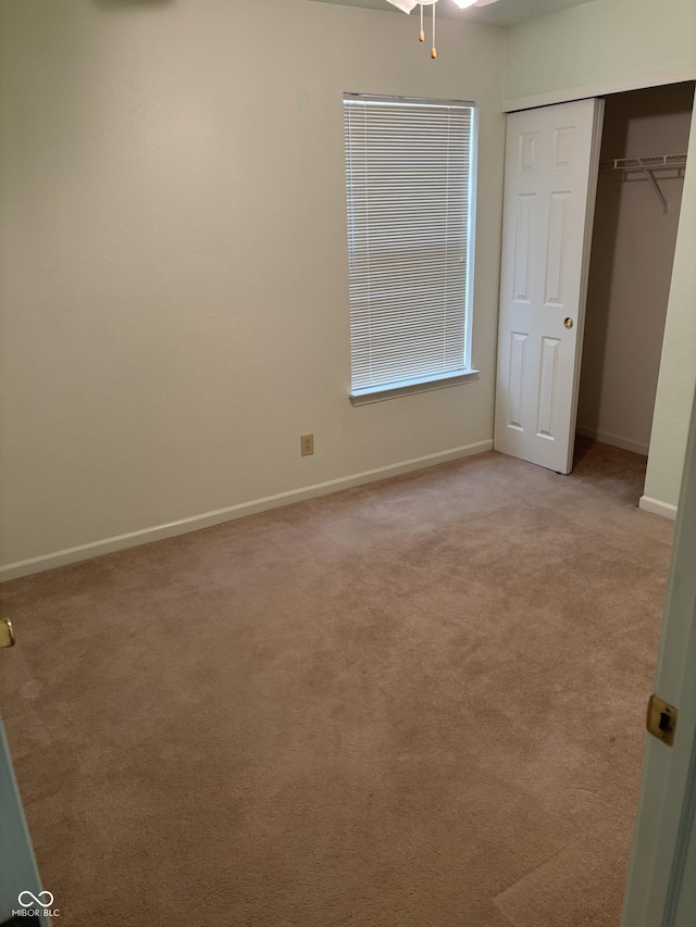 unfurnished bedroom with light carpet and a closet