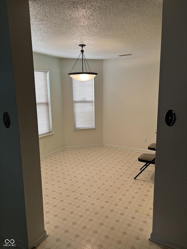 unfurnished dining area with a textured ceiling