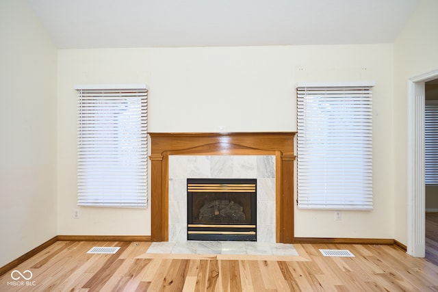 unfurnished living room featuring a tiled fireplace and light hardwood / wood-style flooring