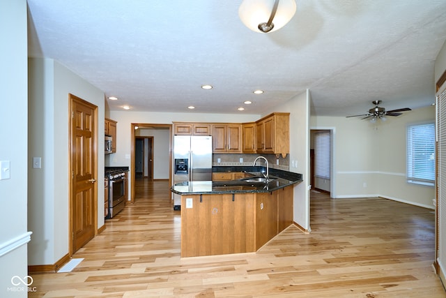 kitchen with kitchen peninsula, appliances with stainless steel finishes, light hardwood / wood-style flooring, and sink