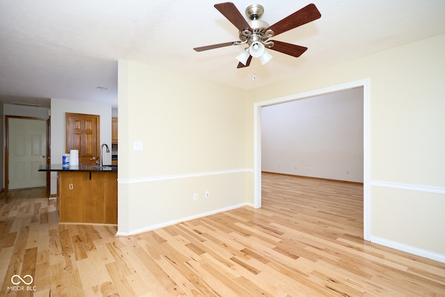 unfurnished room featuring ceiling fan, light hardwood / wood-style flooring, and sink