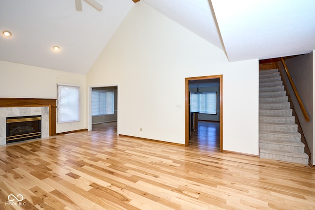 unfurnished living room featuring a fireplace, light wood-type flooring, and high vaulted ceiling