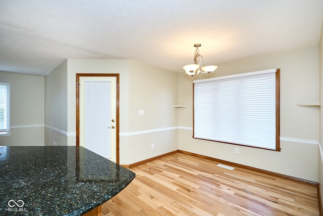 unfurnished dining area with a chandelier and light hardwood / wood-style floors