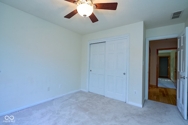 unfurnished bedroom with ceiling fan, a closet, and light carpet