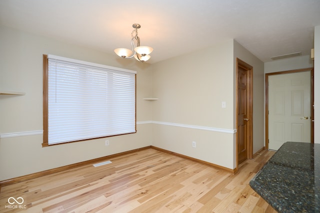 spare room featuring light hardwood / wood-style floors and a chandelier