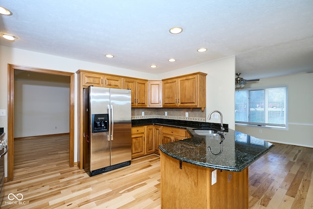 kitchen featuring sink, kitchen peninsula, stainless steel refrigerator with ice dispenser, and light wood-type flooring