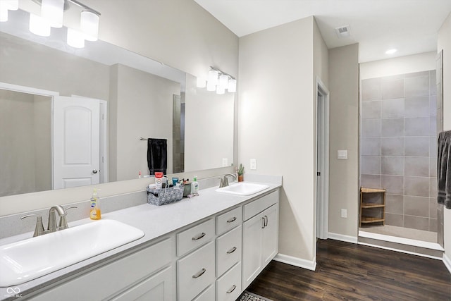 bathroom with tiled shower, wood-type flooring, and vanity