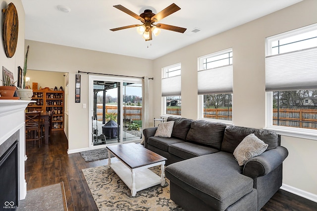 living room with dark hardwood / wood-style flooring, ceiling fan, and a healthy amount of sunlight