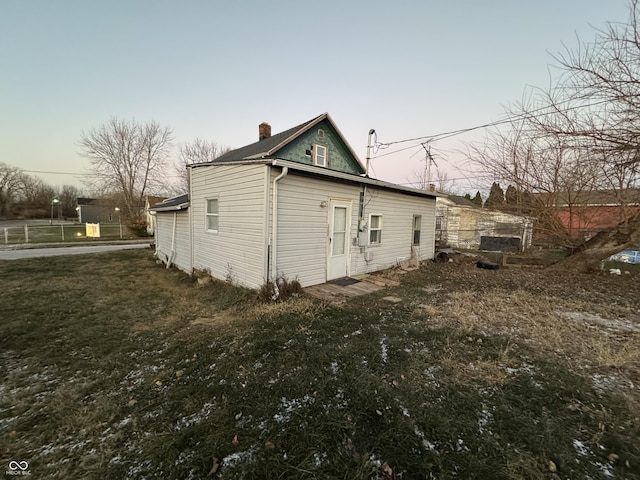 property exterior at dusk featuring a yard