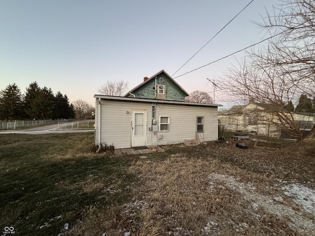 back house at dusk featuring a yard