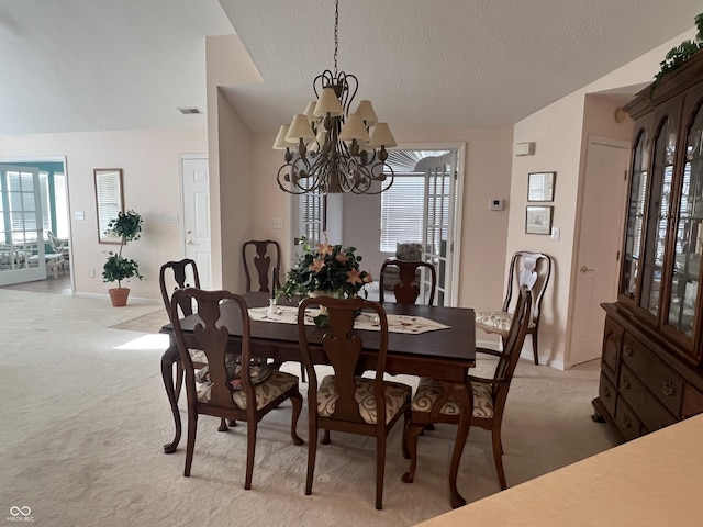 carpeted dining area with plenty of natural light, a chandelier, and vaulted ceiling