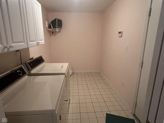 laundry room featuring washing machine and dryer, light tile patterned floors, and cabinets