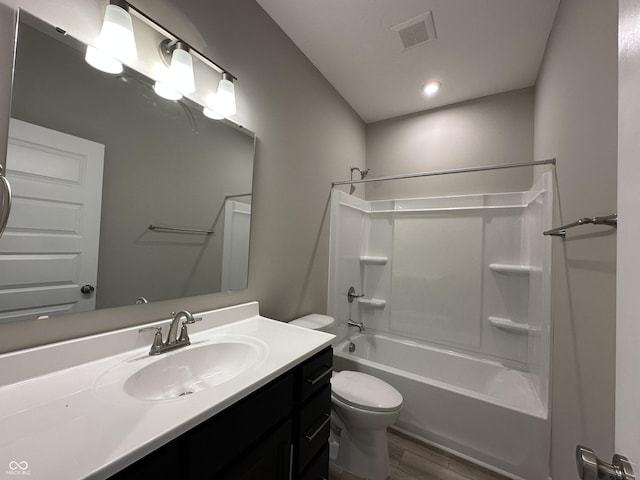 bathroom featuring visible vents, toilet, wood finished floors, shower / bath combination, and vanity