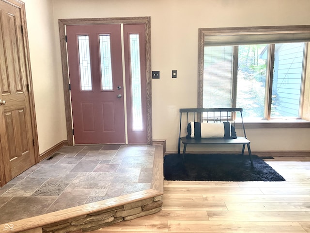 foyer entrance featuring stone tile flooring and baseboards