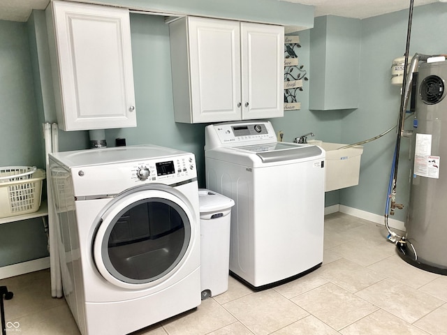 laundry area with baseboards, washing machine and clothes dryer, light tile patterned flooring, cabinet space, and water heater