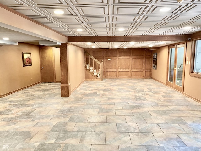 below grade area with stairway, baseboards, an ornate ceiling, and wood walls