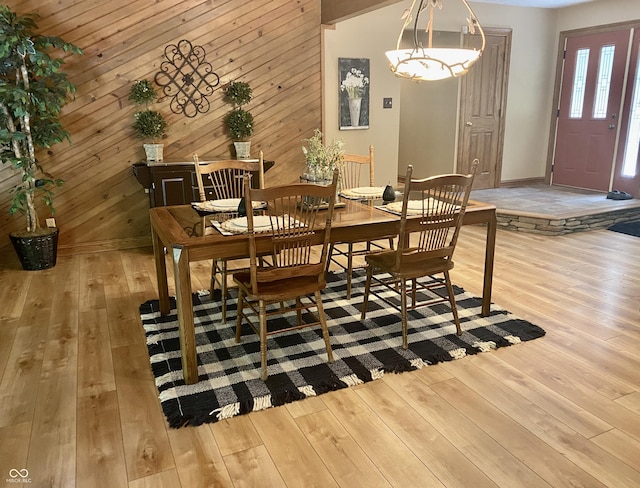 dining area with wood finished floors, baseboards, and wood walls