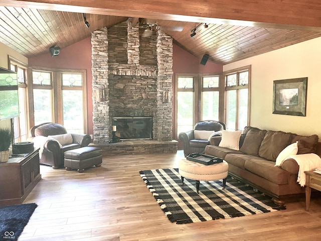 living area featuring a stone fireplace, wood ceiling, wood finished floors, and high vaulted ceiling