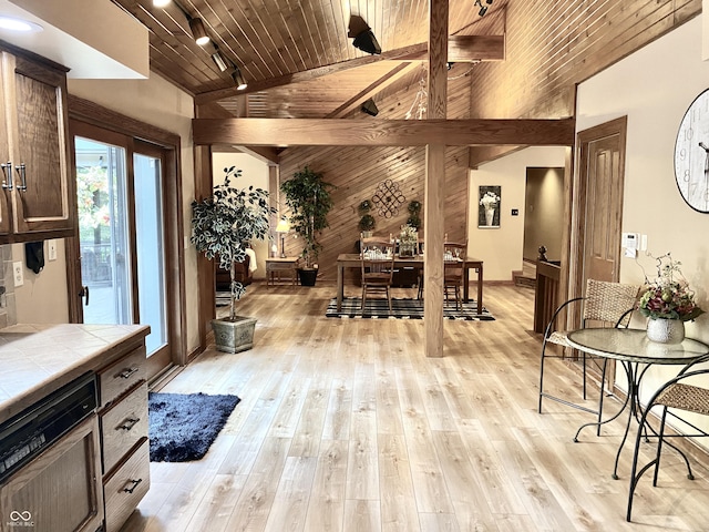 dining area with beamed ceiling, wood walls, wood ceiling, light wood-type flooring, and rail lighting