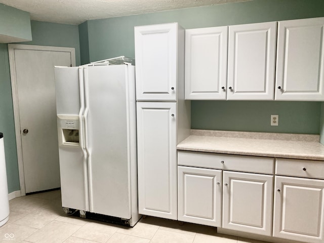 kitchen featuring white cabinetry, light countertops, white fridge with ice dispenser, and a textured ceiling