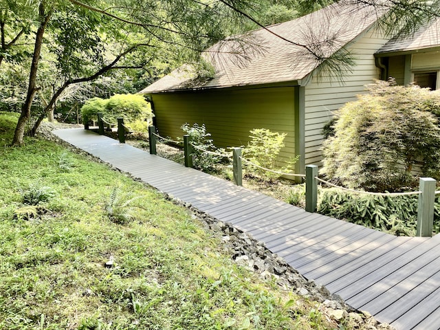 view of side of property featuring a lawn and roof with shingles