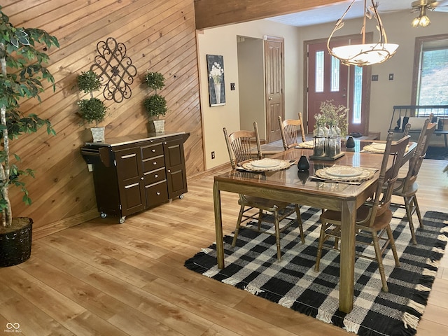 dining space featuring wood walls, light wood-type flooring, and baseboards