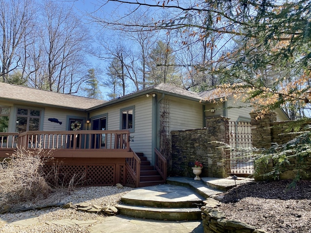 view of property exterior featuring a wooden deck and roof with shingles