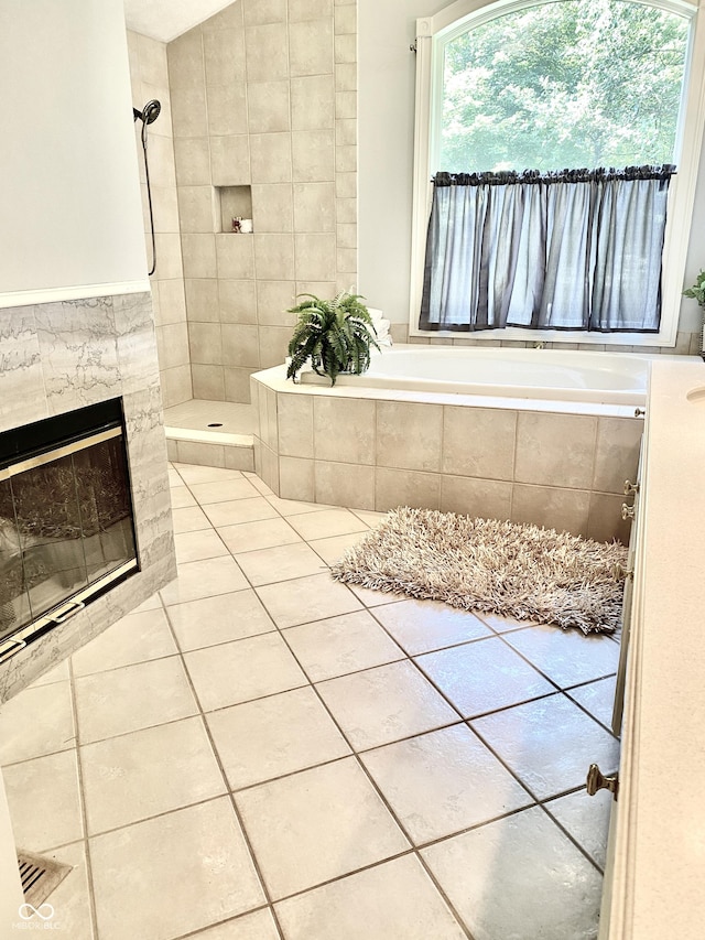 bathroom featuring tile patterned flooring, a bath, a fireplace, and a tile shower