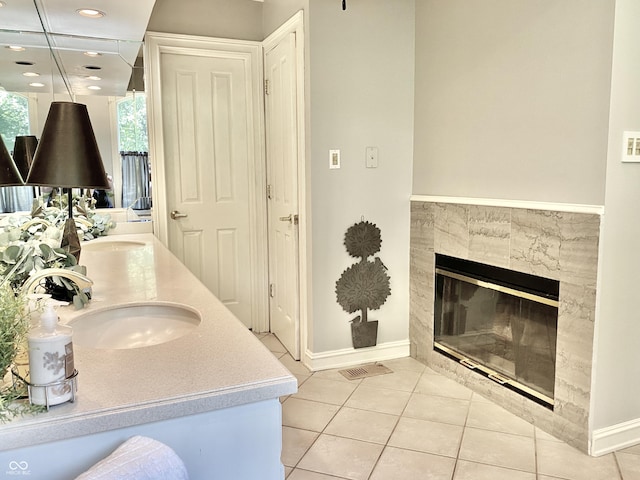 full bathroom with visible vents, double vanity, a fireplace, a sink, and tile patterned flooring