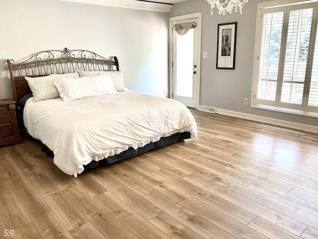 bedroom featuring ornamental molding, wood finished floors, visible vents, and baseboards