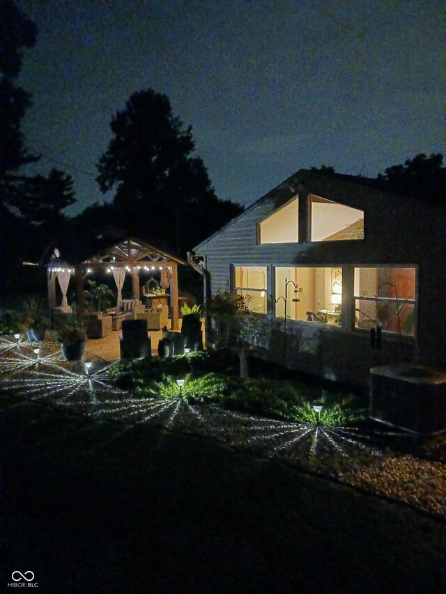 back house at night with cooling unit and a gazebo