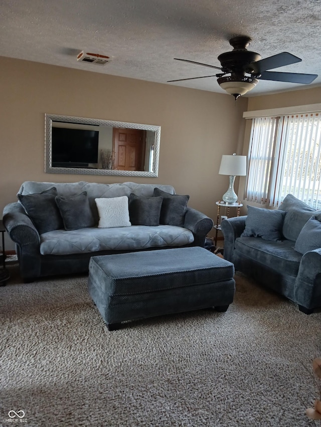 living room featuring ceiling fan, carpet flooring, and a textured ceiling