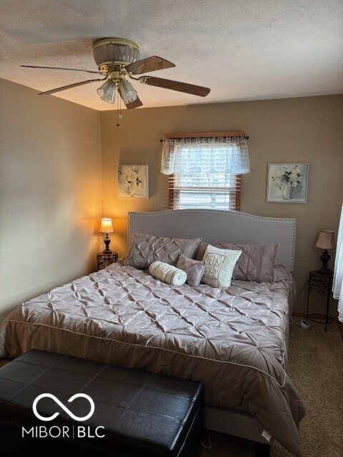 carpeted bedroom featuring ceiling fan and a textured ceiling